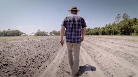 Bryan walks through a dirt field that is ready for planting.