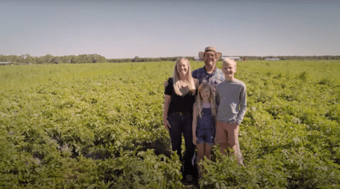 Bryan, his wife, and two children stand in their potato field. 