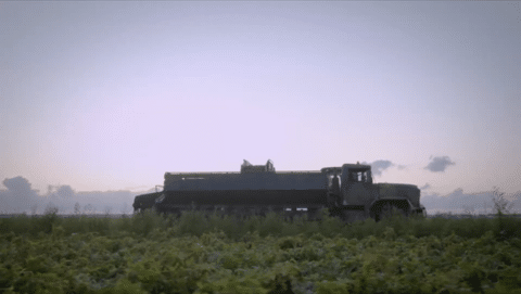 A military-grade truck drives through a potato field early in the morning.